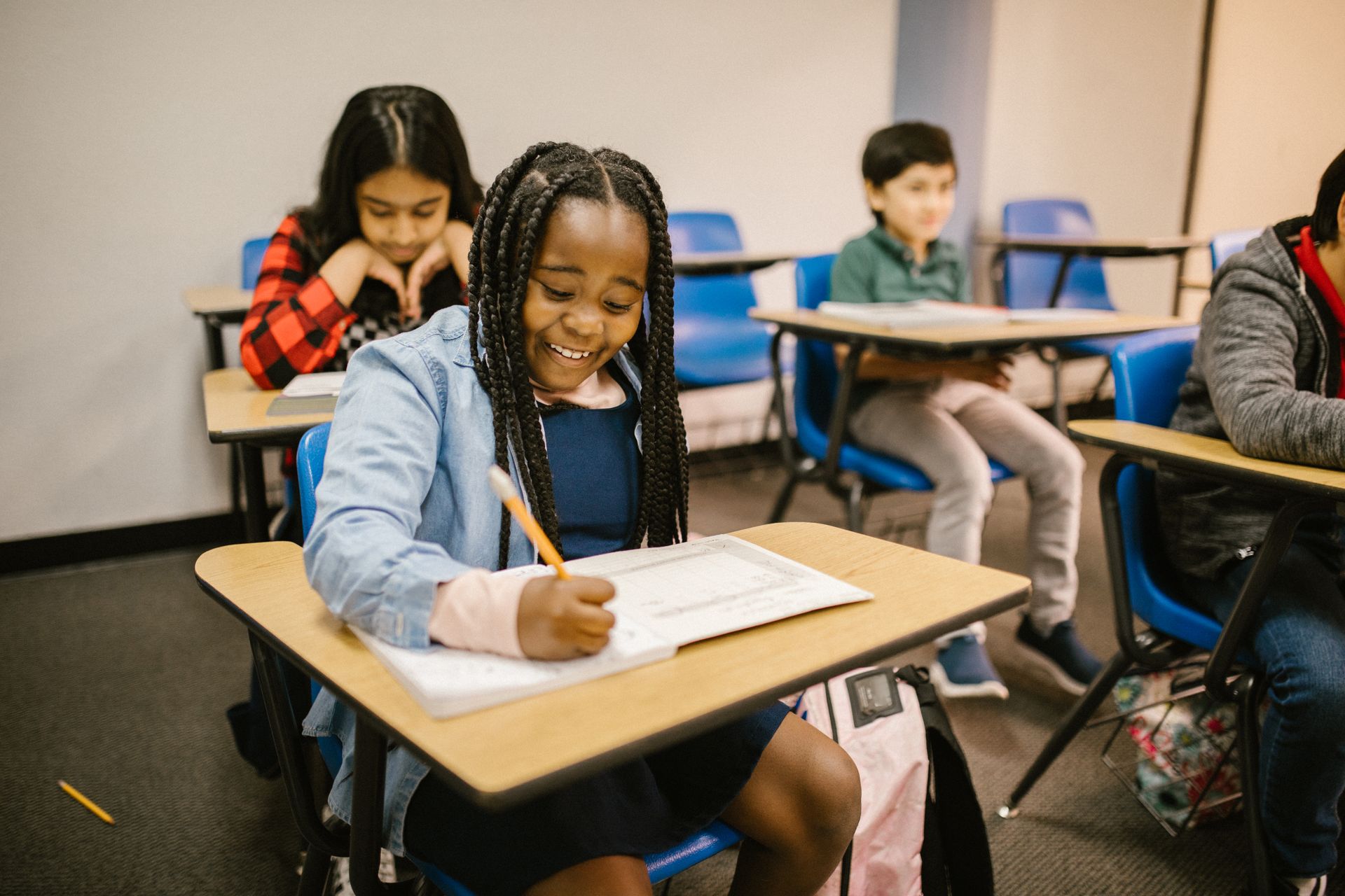 Student writing in a classroom with KStudy